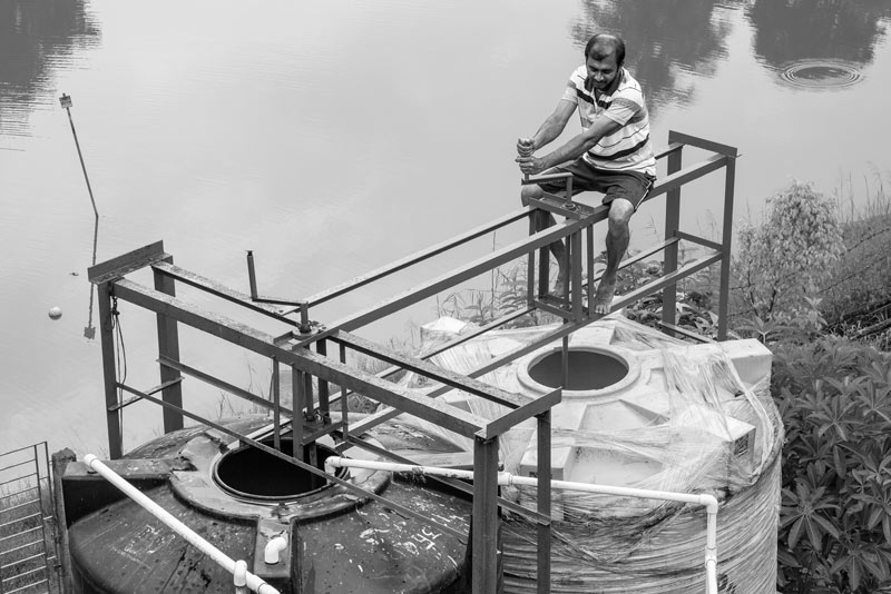 Adding alum and bleaching powder to raw pond water as pre-treatment at the Sulabh Safe Drinking Water plant in Madhusudankati village, North 24 Parganas district, West Bengal